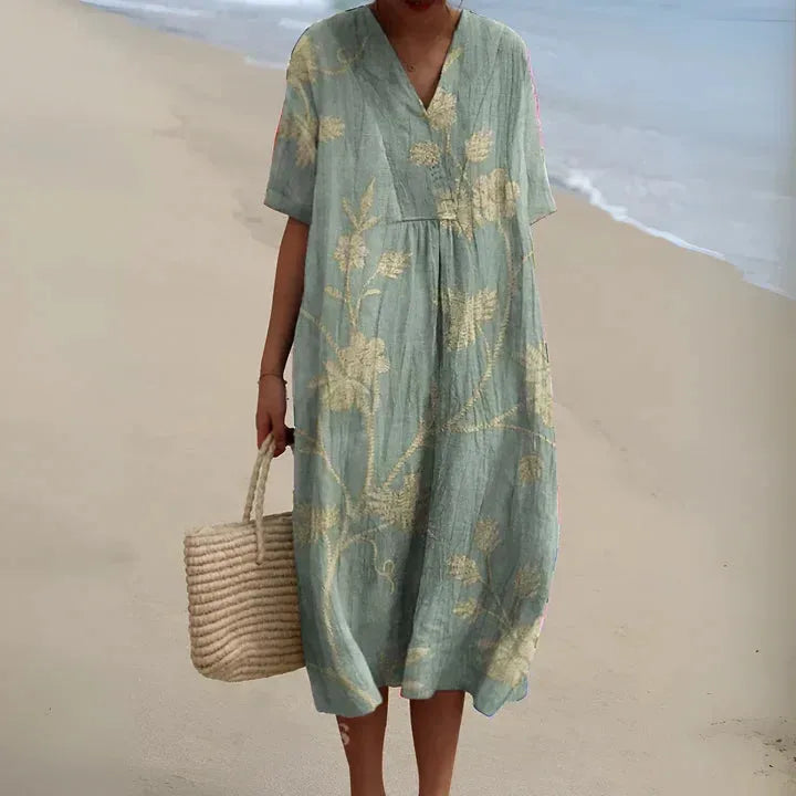 Sage green V-neck midi dress with an allover cream floral print, short sleeves and relaxed silhouette, shown beachside