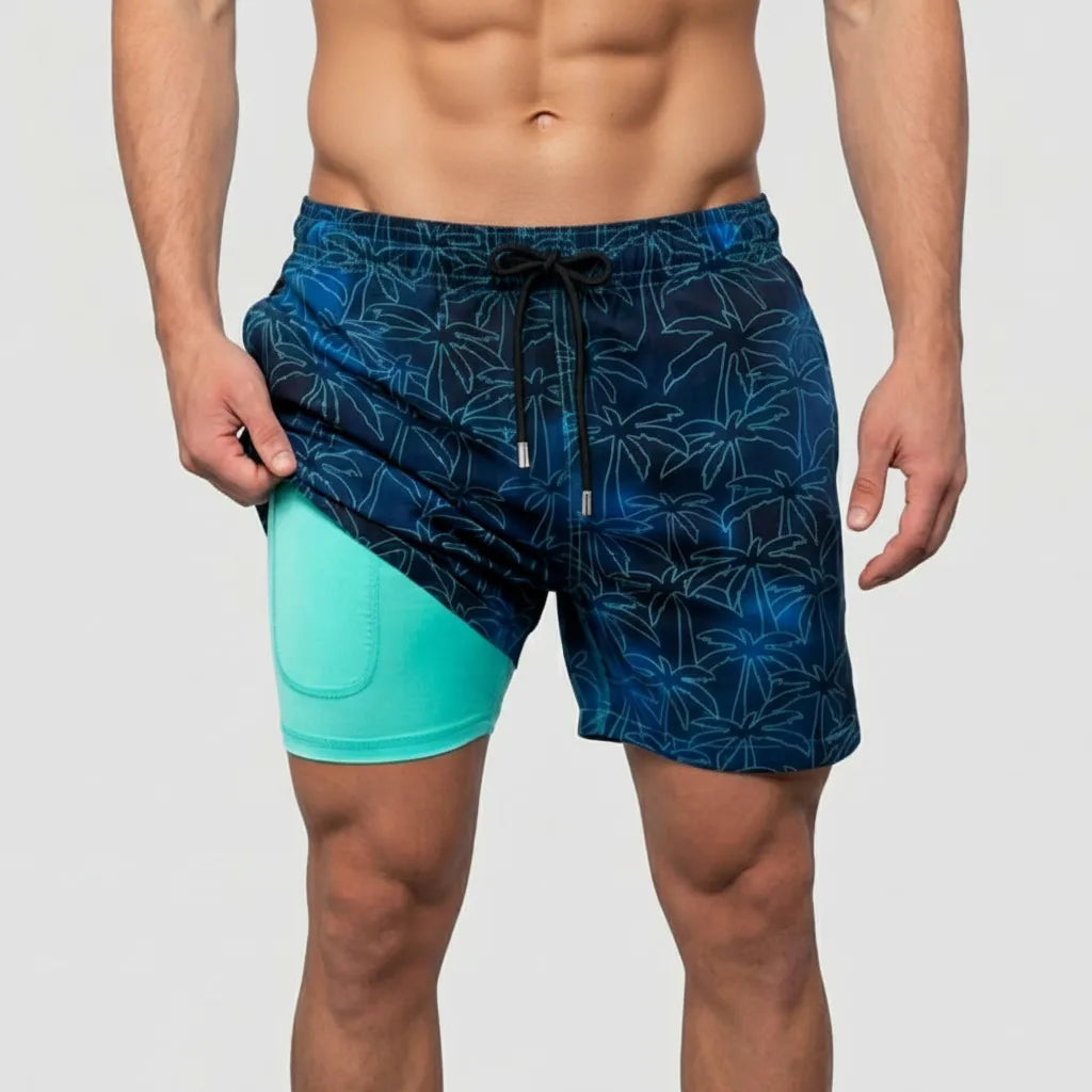 Front view of navy swim shorts with teal palm tree outline print and inner mint compression liner visible at hip