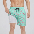 Front view of mint green swim shorts with pink flamingo print, side pocket open showing white compression liner holding a phone