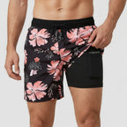 Front view of black swim shorts with pink hibiscus floral print, pocket pulled open to show black compression liner with phone pocket