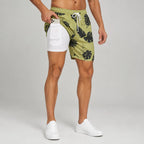Man wearing green tropical leaf print swim shorts with white compression liner and phone in side pocket