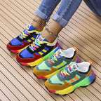 Pair of chunky rainbow sneakers side by side, one in blue and red, one in green and mustard colourway