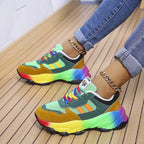 Side view of green and mustard chunky sneaker with rainbow midsole, worn with rolled denim jeans
