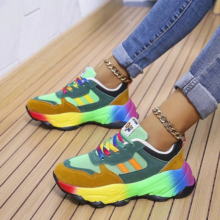 Side view of green and mustard chunky sneaker with rainbow midsole, worn with rolled denim jeans