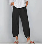 Front view of black linen-blend pants with relaxed wide leg and tulip hem, paired with knit sandals