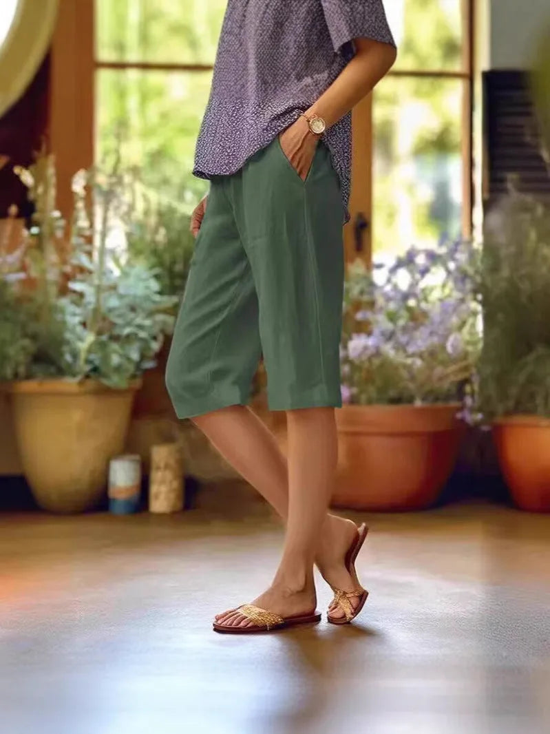 Dark green capri pants front view highlighting relaxed fit through hip and thigh with side pocket opening