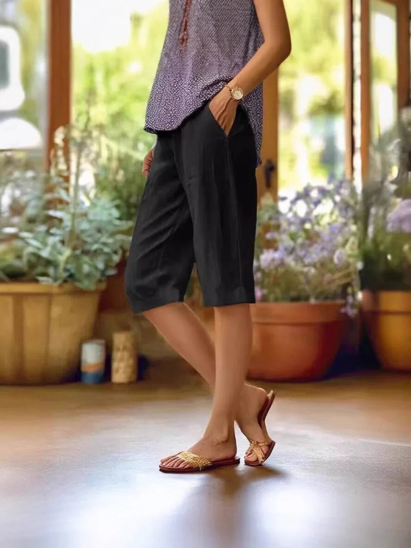 Black linen-style capri pants with deep side pocket, paired with printed top and heeled sandals