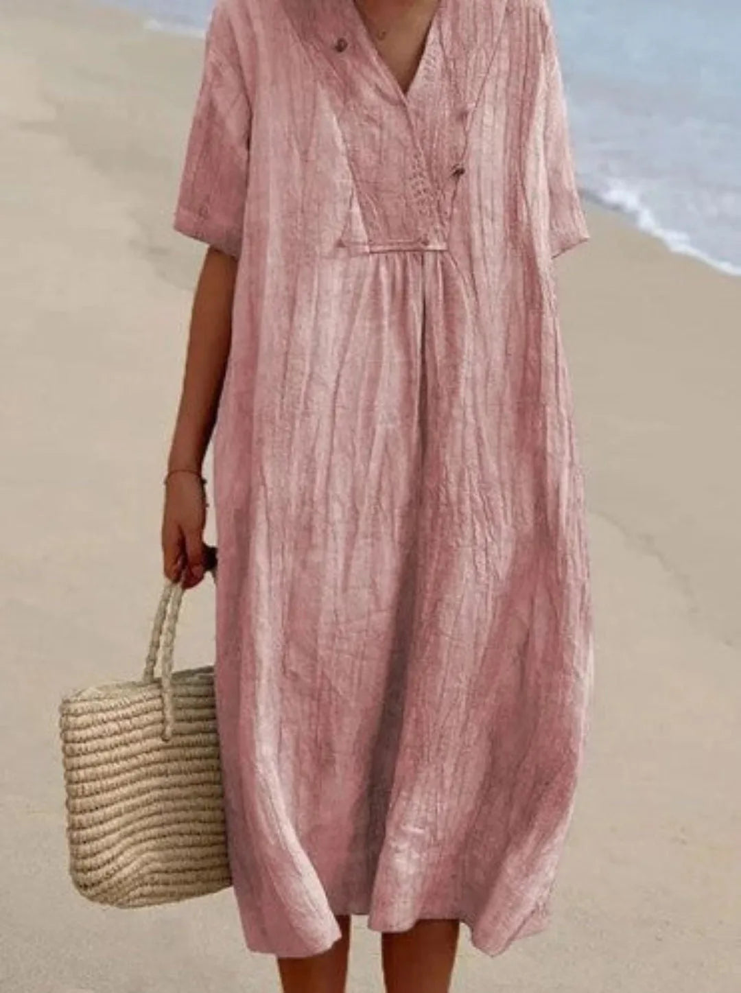 Soft pink crinkled linen-look midi dress with V-neckline, short sleeves and gathered waist detail at the beach