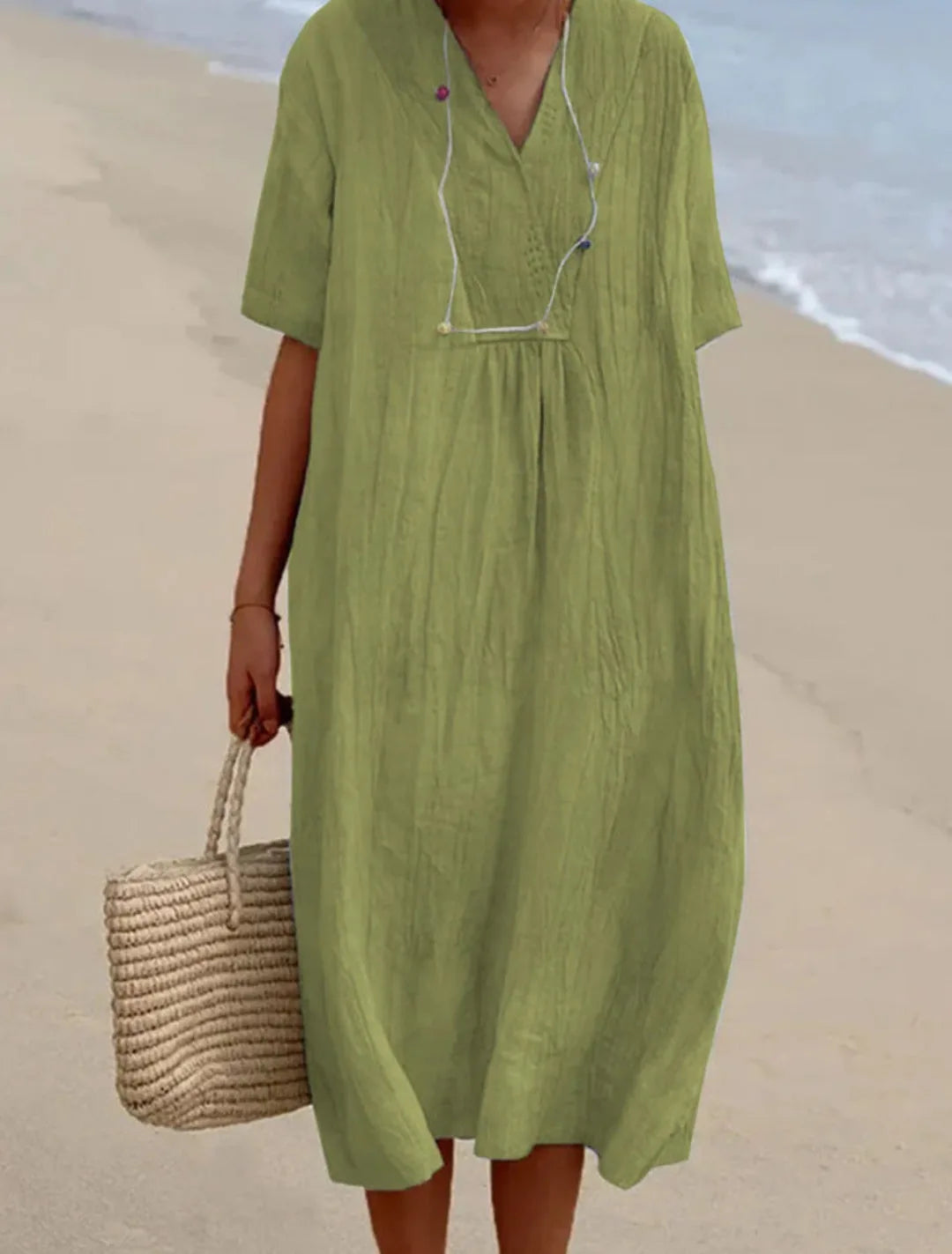 Light green V-neck midi dress with relaxed wrap front and short sleeves, styled with a straw tote bag