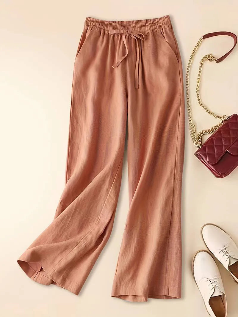Terracotta relaxed linen pants shown full length with drawstring waist, side pockets and white loafers nearby