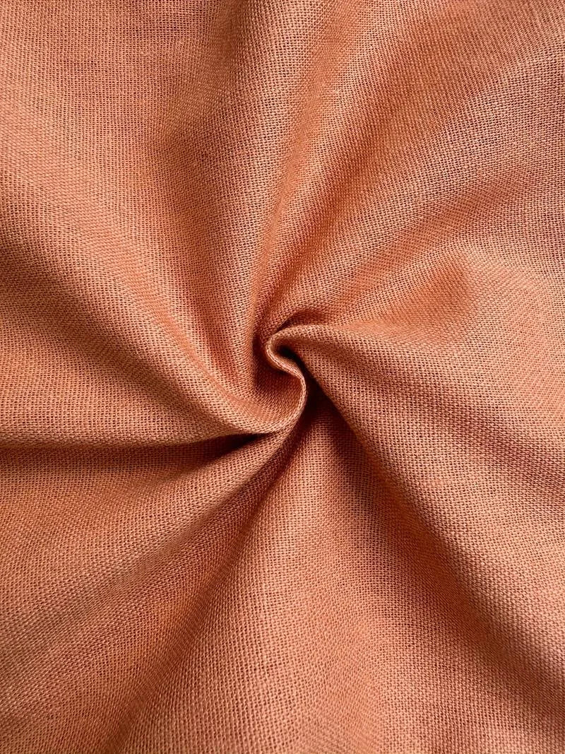 Close-up of the woven linen fabric texture in a warm terracotta tone