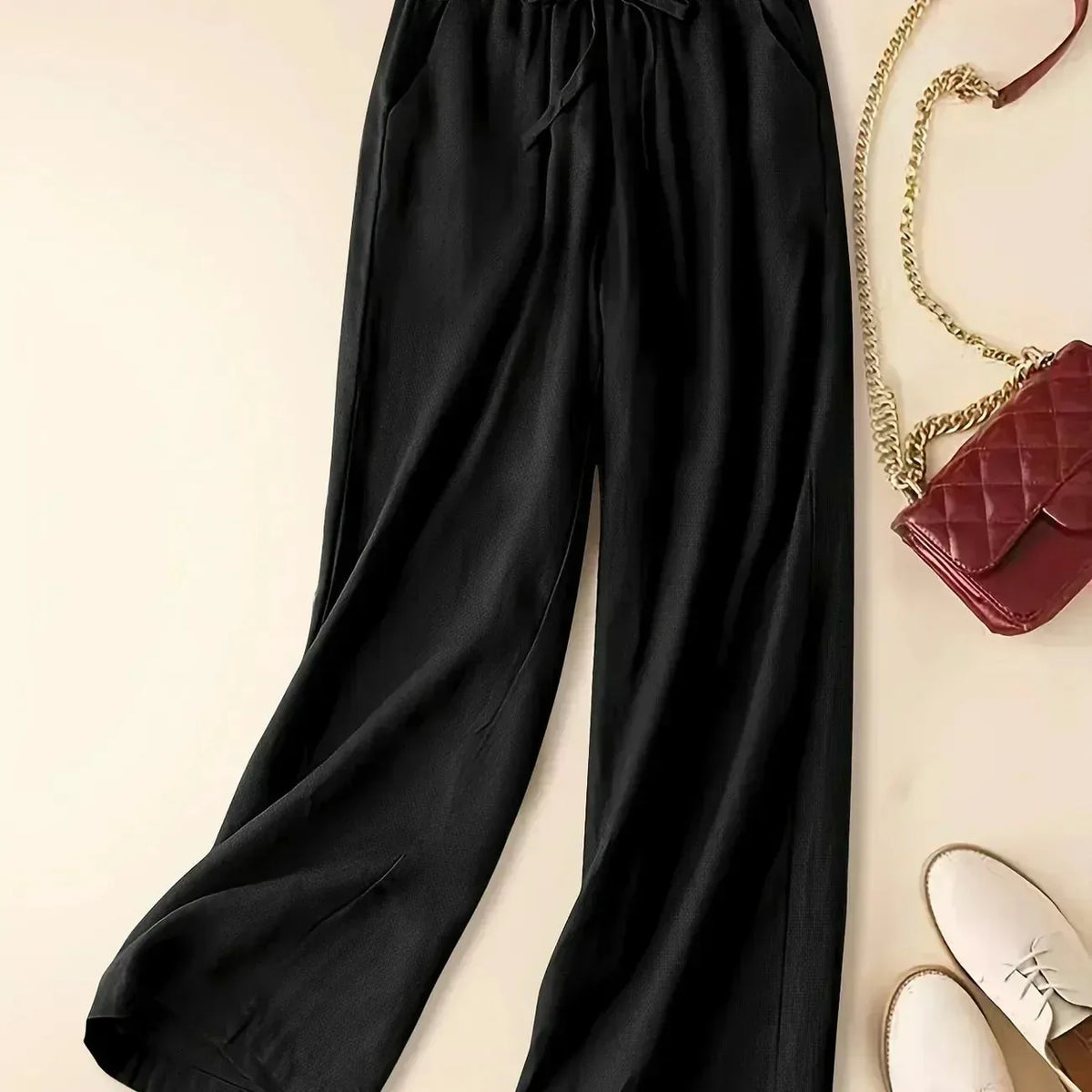 Black relaxed linen pants shown from the waist down with drawstring tie and wide leg silhouette