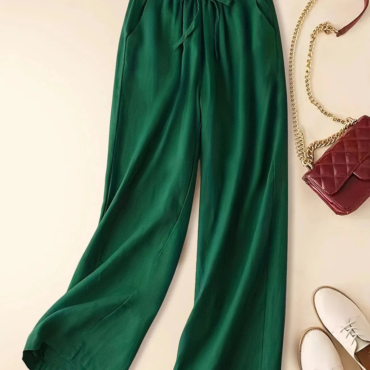 Green relaxed linen pants shown from the waist down with soft drape and wide straight leg