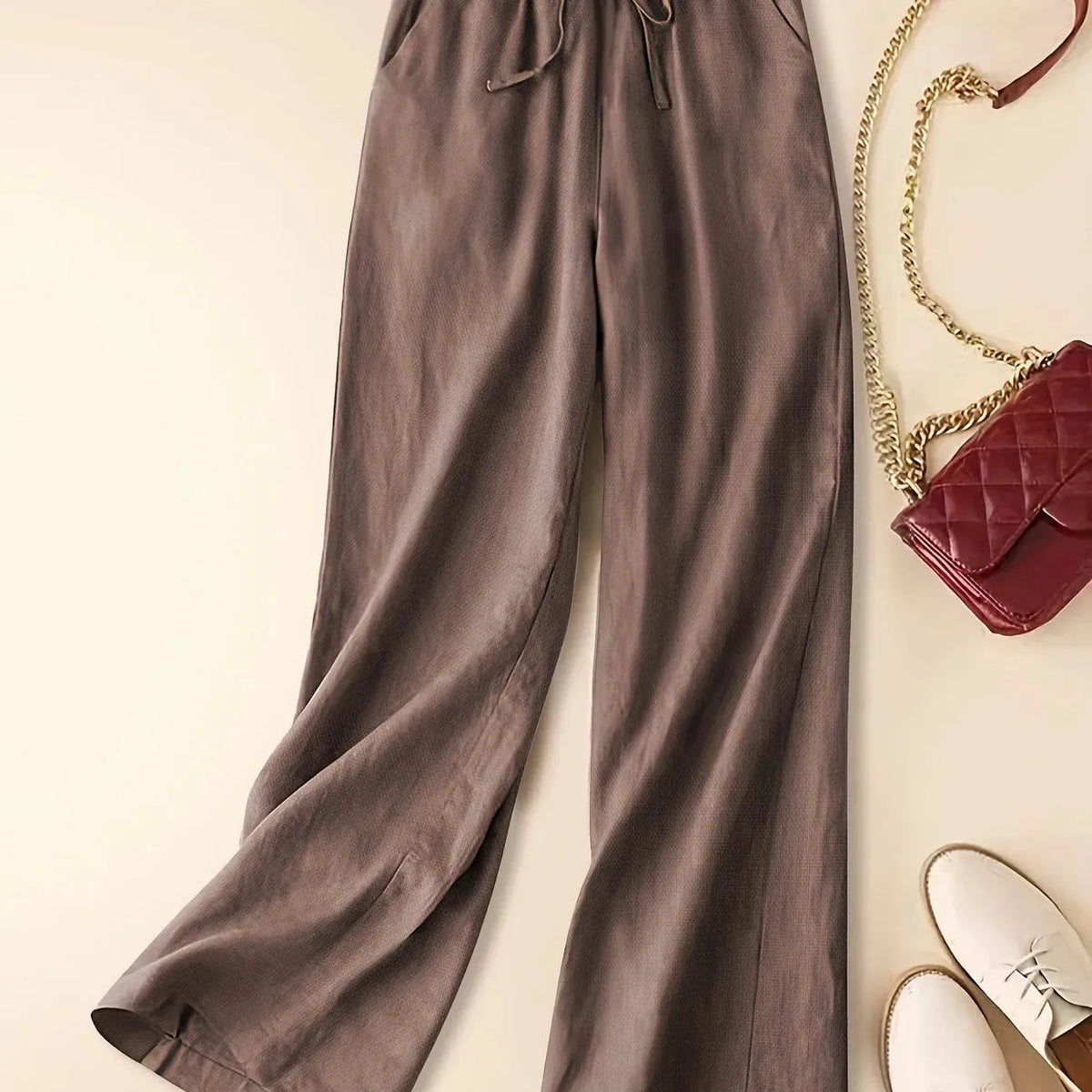 Brown relaxed linen pants shown from the waist down highlighting the flowing wide leg fabric