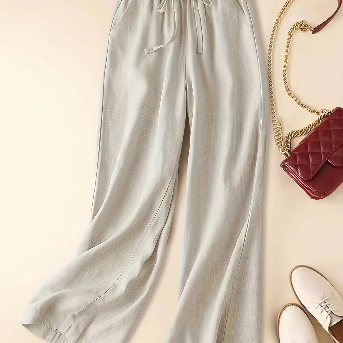 Beige relaxed linen pants shown from the waist down with drawstring waist and relaxed wide fit