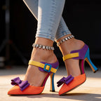 Front angle of both colour-block heels on model, highlighting orange toe box and purple satin bow
