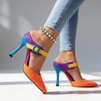 Close-up side profile of ankle strap buckle and teal stiletto heel against a light grey backdrop