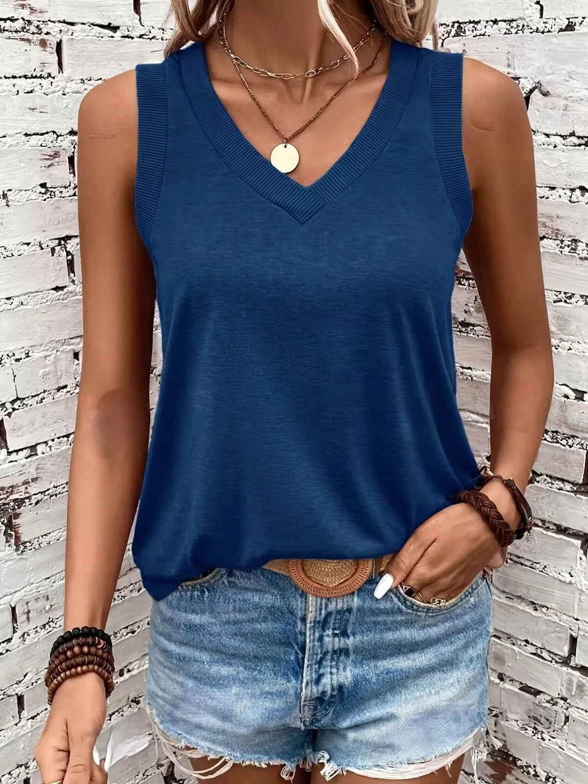 Front view of the navy blue V-neck singlet with ribbed neckline worn with a woven belt