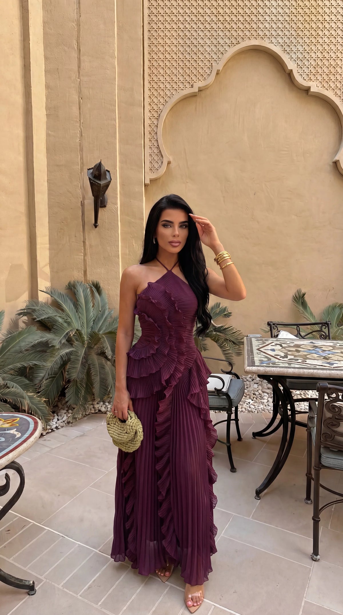 Model walking outdoors in yellow pleated maxi dress showing the asymmetrical ruffle skirt in motion