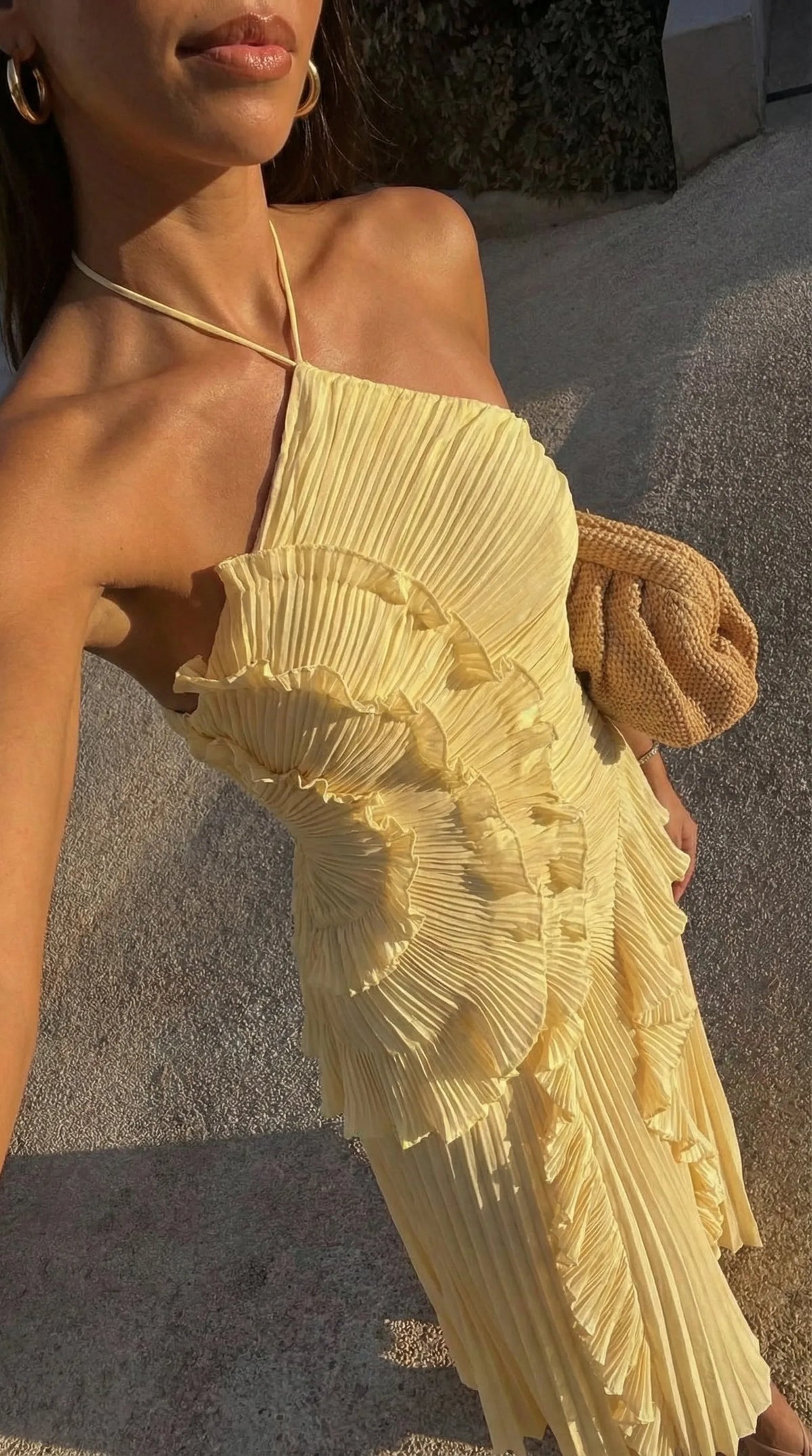 Close-up of yellow pleated bodice showing sculptural ruffle trim and halter neck tie detail