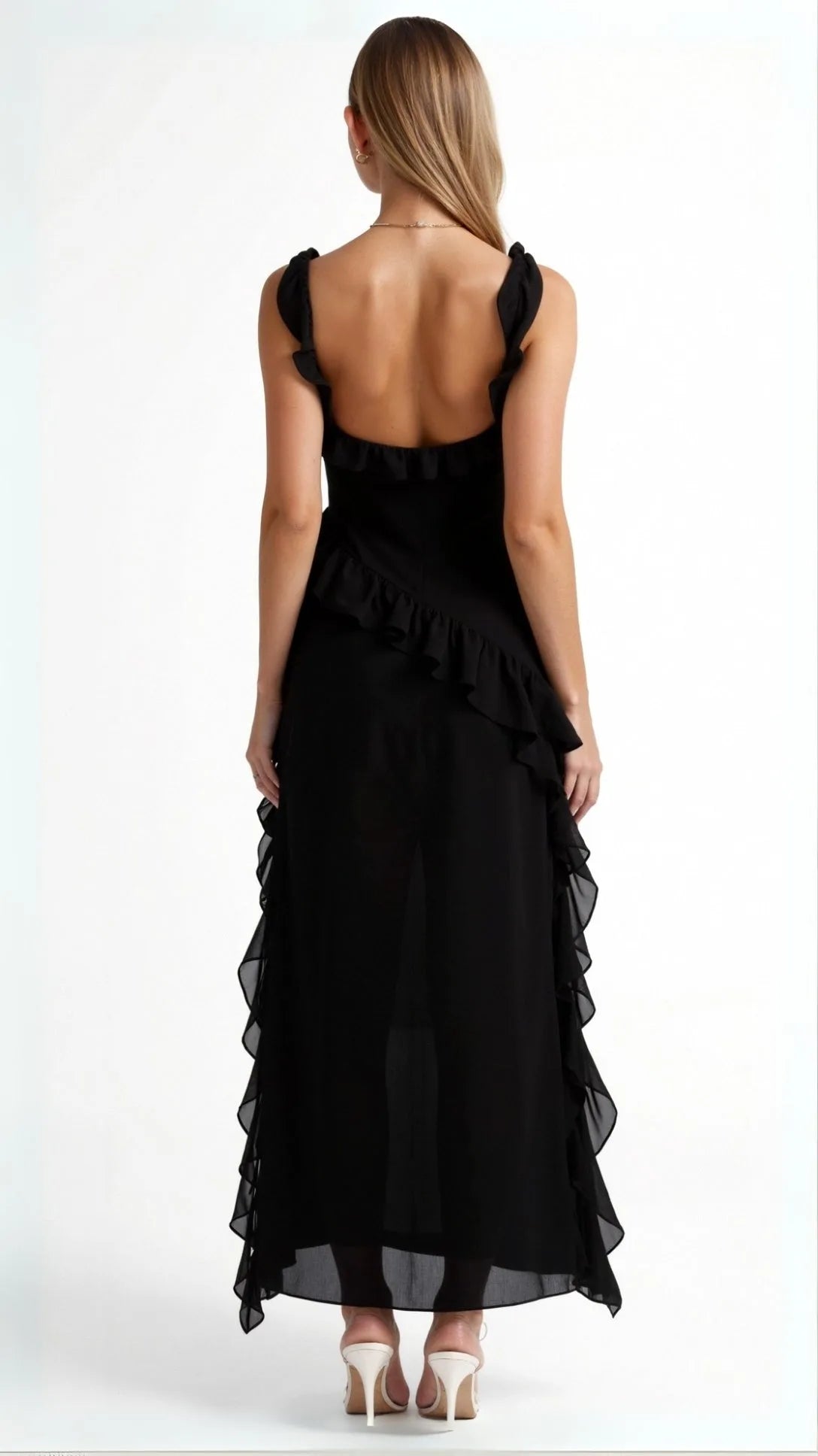 Back view of black ruffled maxi dress showing low scoop back and ruffle trim cascading down the asymmetric overlay