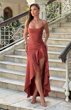 Full-length front shot on a staircase, brick-red satin gown with spaghetti straps and gathered skirt in daylight