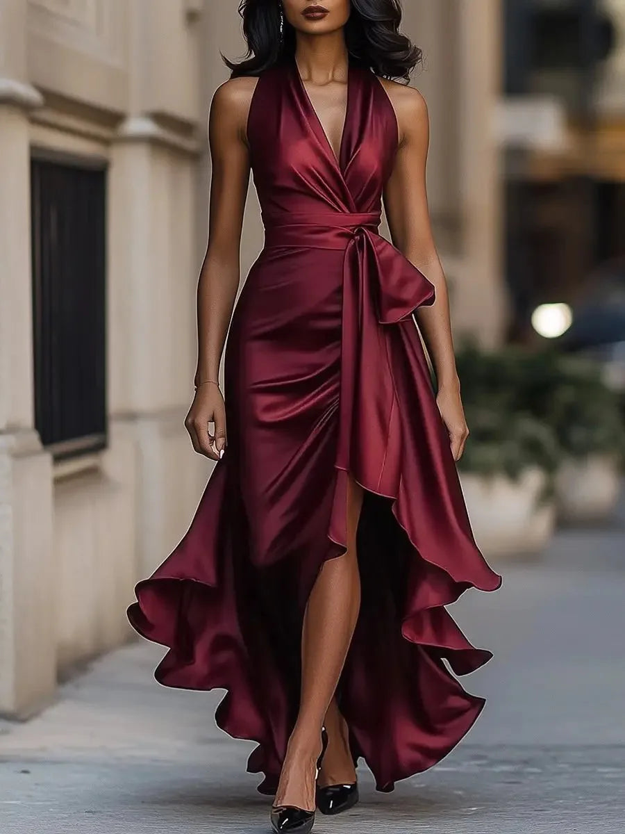 Burgundy satin halterneck maxi dress with plunging neckline, bow waist and voluminous ruffled hemline