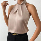 Close-up front view of camel satin halter top with twisted knot neckline, worn with black jeans and a gold belt