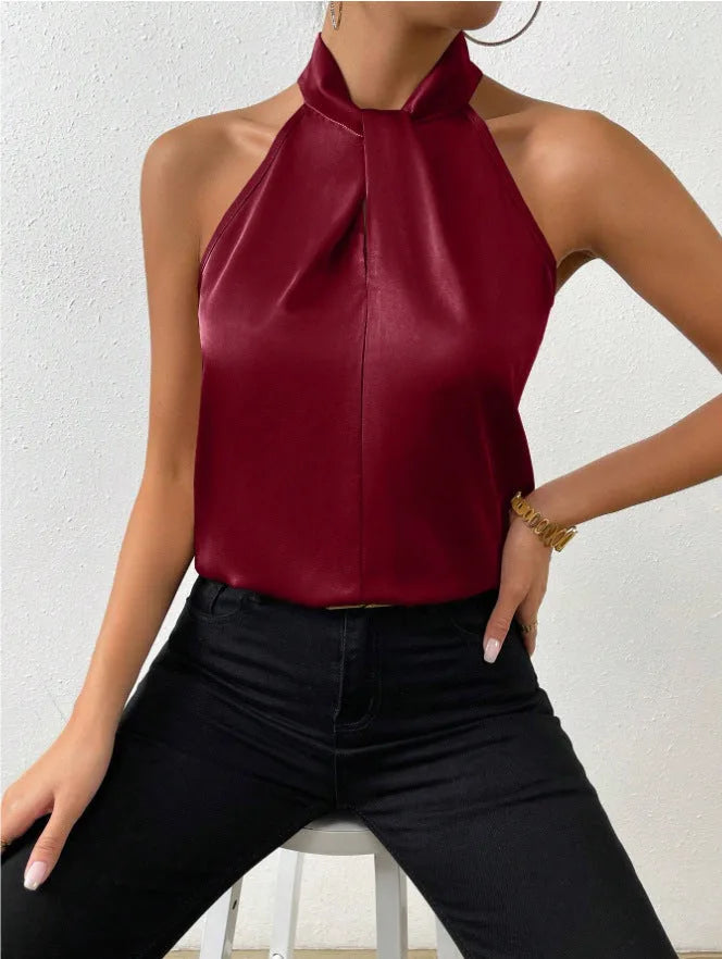 Deep burgundy satin halter top with twisted neckline, seated pose showing the fluid drape of the fabric