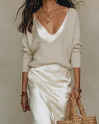 Close-up of the white satin slip dress layered under a cream ribbed V-neck knit jumper