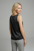 Woman wearing a white satin V-neck singlet, close-up on the neckline and shoulder straps