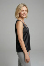 Full-length view of a woman in a black satin singlet paired with charcoal grey trousers