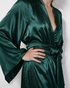 Woman adjusting the sash of the red satin robe, highlighting the wide kimono sleeve detail