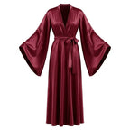 Woman in red satin robe standing against a plain wall, showing the overall silhouette