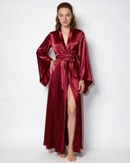 Detail of the hem and leg slit on the red satin robe, showing the fabric fall
