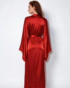 Rear view of woman wearing red satin robe, showing the smooth drape across the back and wide sleeves