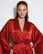 Close-up of woman's face and shoulders wearing red satin robe with tied waist sash