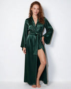 Woman modelling the forest green satin robe, standing with one hand on hip, leg slit visible