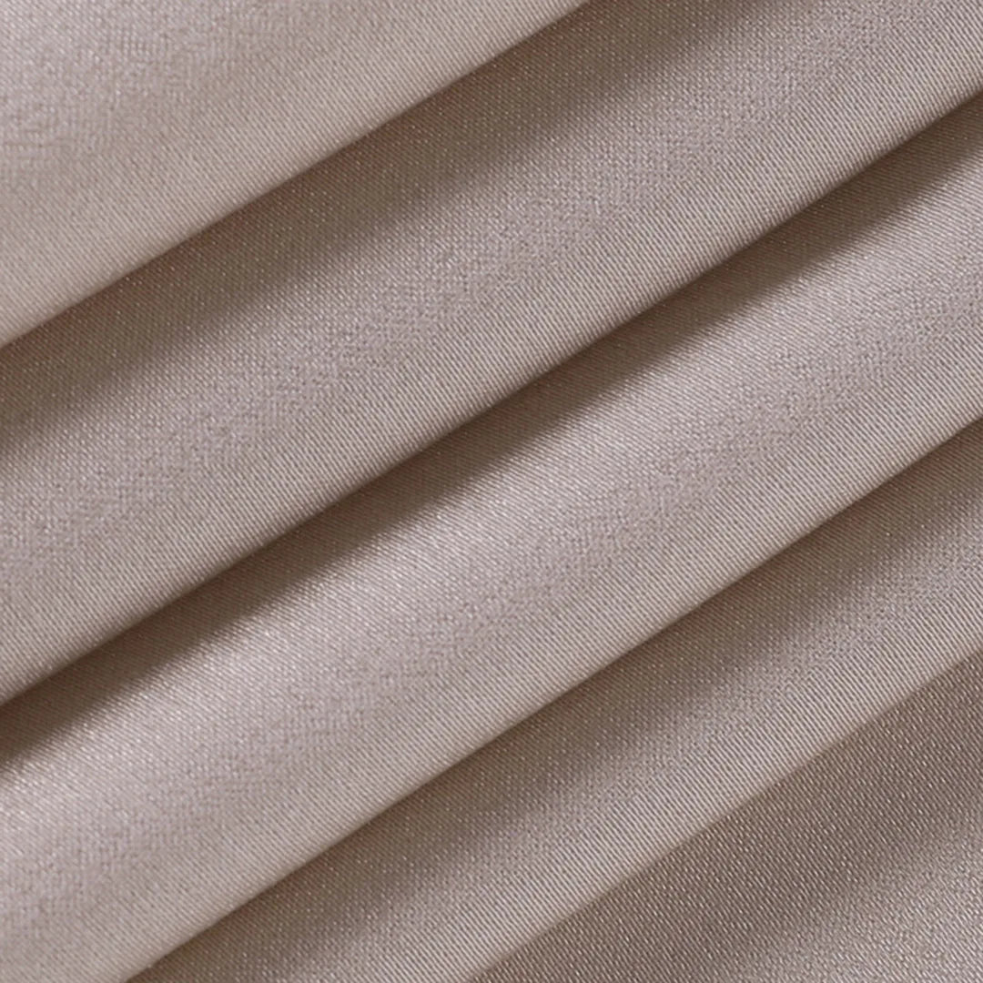 Flat lay close-up of the adjustable spaghetti strap and slider on the beige satin dress