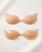 Two nude silicone adhesive bra cups shown matte-side up and gel-side up, revealing the smooth inner texture
