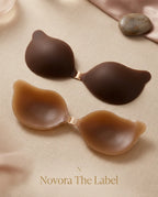 Deep brown and caramel tan adhesive bra cups displayed side by side on linen fabric with the Novora The Label branding