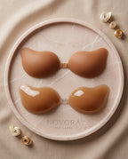 Caramel tan adhesive bra cups shown both matte-side up and gel-side up on a round marble dish with Novora The Label etching