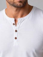 Close-up of white Henley T-shirt collar showing brown button placket and ribbed neckline stitching