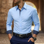 Man wearing a light blue slim-fit dress shirt with navy patterned contrast collar, open cuff and black belt