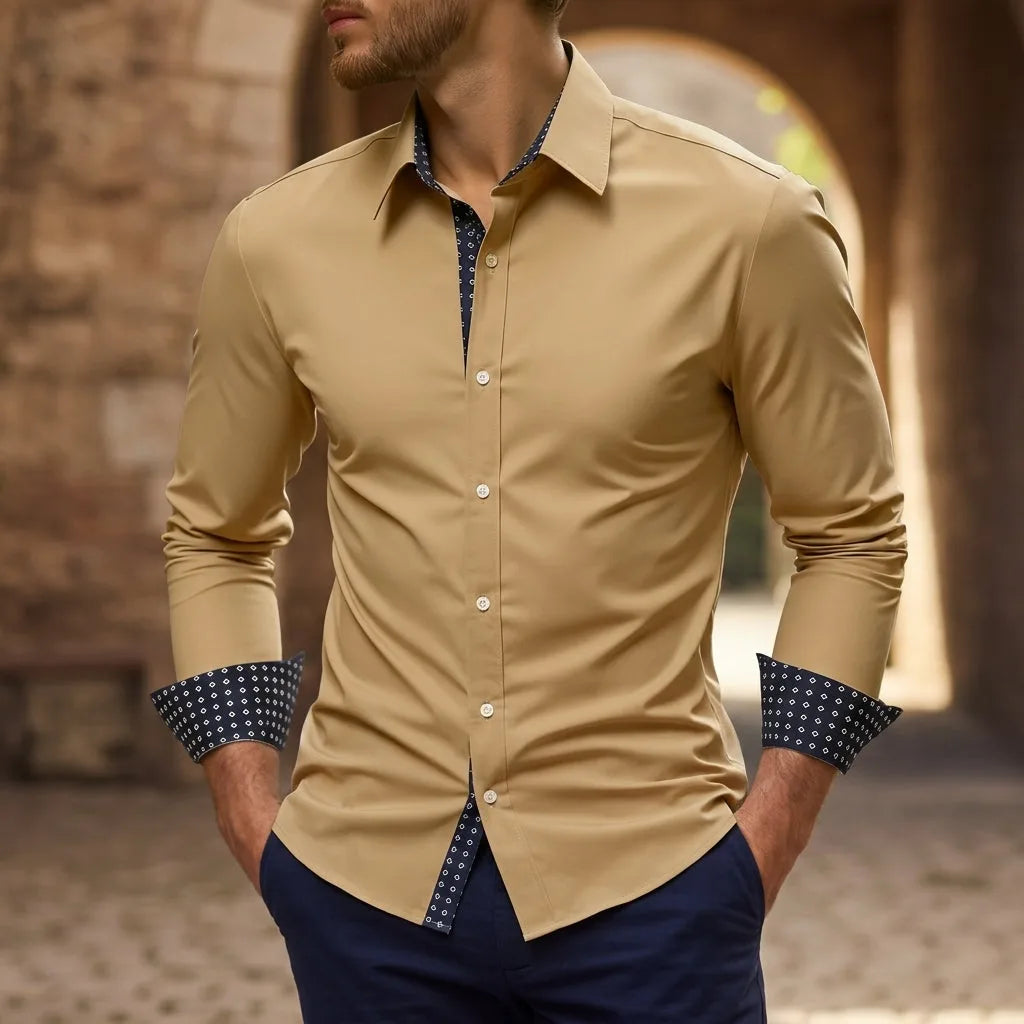 Man with hands in pockets wearing a tan beige slim-fit shirt with navy diamond-print collar and cuffs