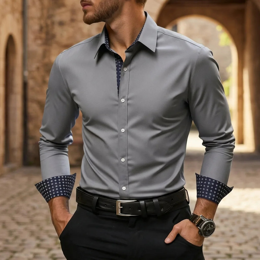 Man wearing a grey slim-fit dress shirt with navy patterned contrast cuffs and a black leather belt