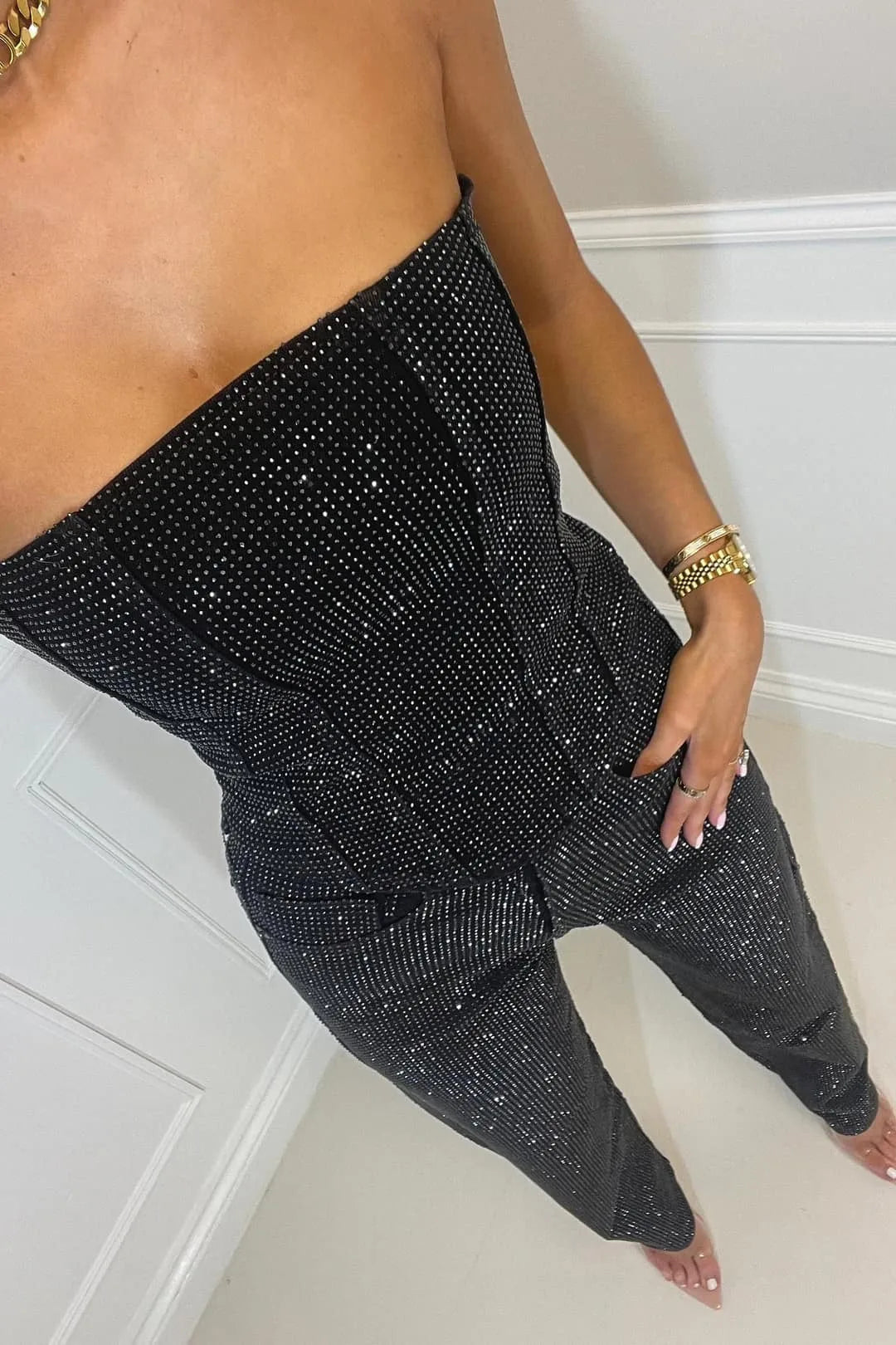 Close-up of the black strapless corset top and high-waist trousers showing the fine all-over sparkle texture