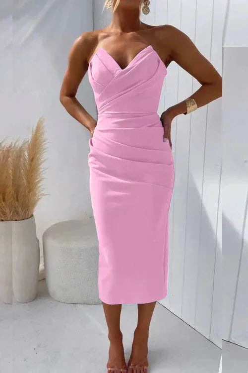 Model standing with hands on hips wearing the strapless ruched midi dress with ankle-strap heels