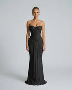 Front view of a strapless black sequined gown with beaded corset bodice, draped waist tie and sleek floor-length mermaid skirt