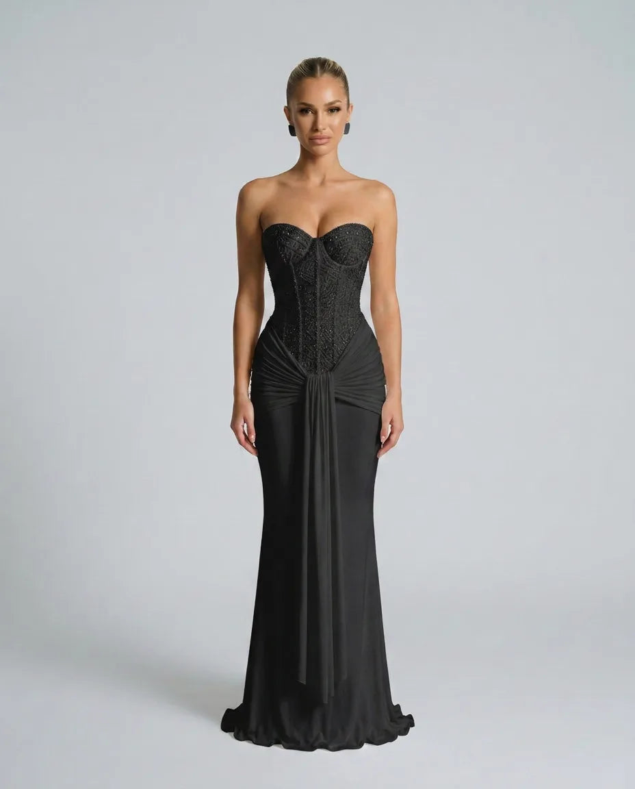 Front view of a strapless black sequined gown with beaded corset bodice, draped waist tie and sleek floor-length mermaid skirt